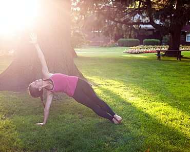 Woman balancing in yoga pose in park, Toronto, Ontario, Canada