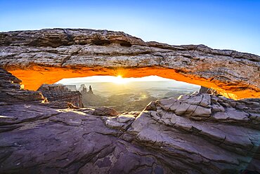 Sunrise at Mesa Arch in Canyonlands National Park at sunrise, the sun lighting the glowing sandstone underside of the arch