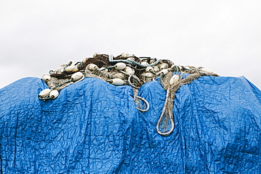 A blue tarpaulin covering stacked commercial fishing nets on the dockside at Fisherman's Wharf, Seattle, Seattle, Washington, USA