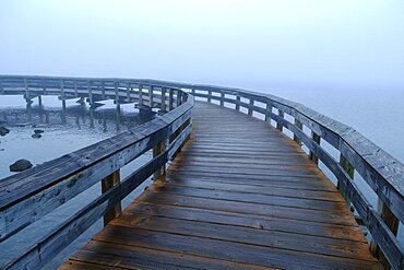 A boardwalk across water, mist rising from the sea