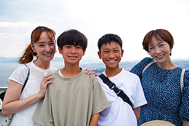 Four Japanese people on a outing, two mature women and two 13 year old boys, in a row, on a viewing platform.