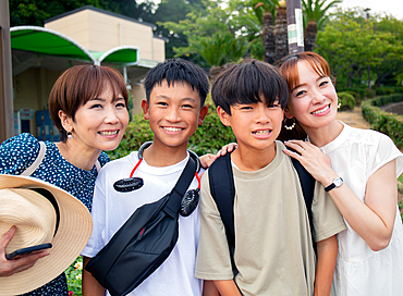 Four Japanese people on a outing, two mature women and two 13 year old boys, in a row, laughing.