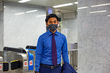 A young businessman in the city, on the move, wearing a face mask.