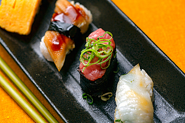 Sushi platter, a selection of raw fish and rice snacks with chopsticks.