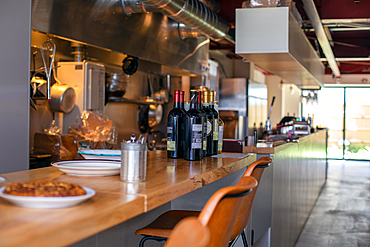 A restaurant kitchen and service counter, bottles of red wine.