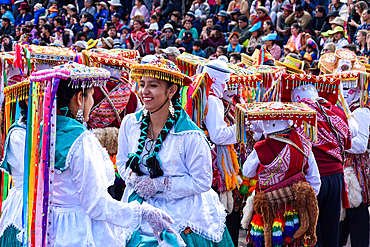 Cusco, a cultural fiesta, people dressed in traditional colourful costumes with masks and hats, brightly coloured streamers.