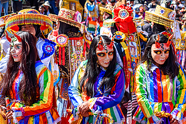 Cusco, a cultural fiesta, people dressed in traditional colourful costumes with masks and hats, brightly coloured streamers.