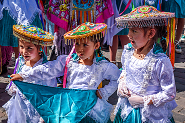 Cusco, a cultural fiesta, people dressed in traditional colourful costumes with masks and hats, brightly coloured streamers.