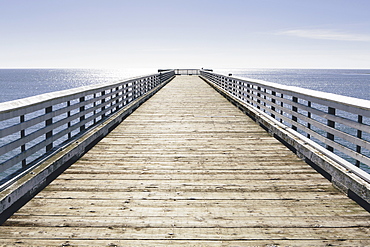 A long pier with railings extending out over the Pacific Ocean leading to the horizon, San Luis Obisbo County, California, USA