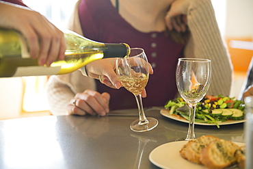 A young man and woman sitting together having a meal and drinking wine, Stone Ridge, New York, USA