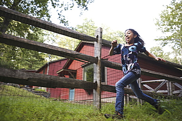 A farm paddock fence. A young girl running around, Woodstock, New York, USA