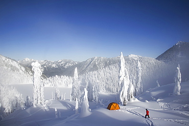 Michael Hanson walks through deep powder to his campsite in the snow covered Cascade Mountains overlooking Snow Lake, Cascade Mountains, Washington, USA