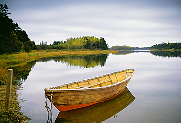 A small wooden dory or rowing boat moored on flat calm water, in Savage harbour on Prince Edward Island in Canada, Savage Harbor, Prince Edward Island, Canada