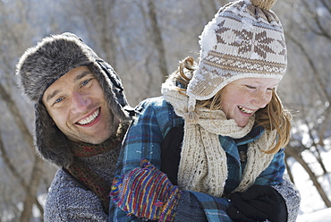 Winter scenery with snow on the ground. A young girl with a bobble hat and scarf and a man hugging her, Provo, Utah, USA