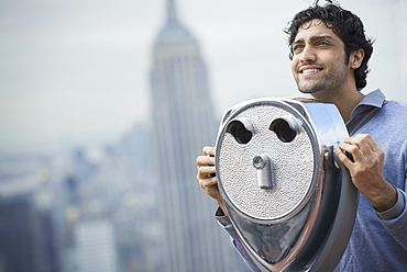 New York City. An observation deck overlooking the Empire State Building. A young man looking through a telescope over the city, New York city, USA