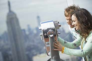 New York City. An observation deck overlooking the Empire State Building. A young couple looking through the telescope, New York city, USA