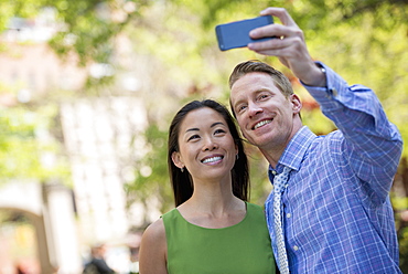 A couple, a man and woman taking a selfy with a smart phone.