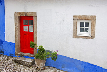 A red painted door of an old house in a street in Sonega, Sonega, Portugal