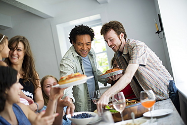 A family gathering for a meal. Adults and children around a table. 