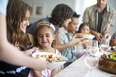 A family gathering for a meal. Adults and children around a table. 