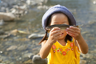 Young girl wearing a summer hat, holding a fish, Kyoto, Honshu Island, Japan