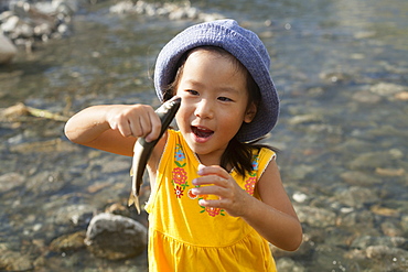 Young girl wearing a summer hat, holding a fish, Kyoto, Honshu Island, Japan