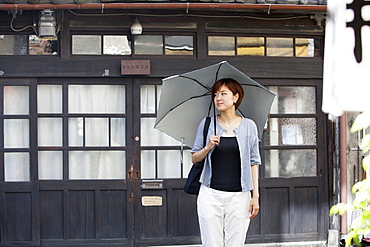 Woman standing outdoors, holding an umbrella, Osaka, Japan