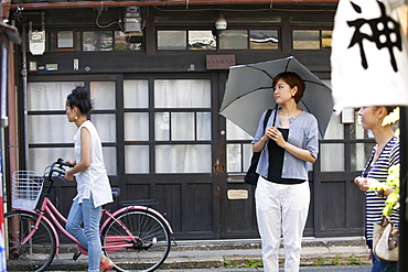 Woman standing outdoors, holding an umbrella, Osaka, Japan