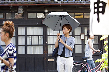 Woman standing outdoors, holding an umbrella, Osaka, Japan