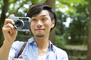 A man in a Kyoto park holding a camera, taking a picture, Kyoto, Honshu Island, Japan