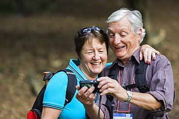 A mature couple looking at a digital camera, laughing, England