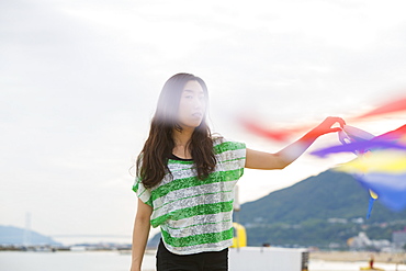 A woman on a beach in Kobe holding paper streamers. , Kobe, Japan