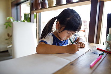 Girl with pigtails sitting at a table, drawing with felt tip pens, Osaka, Japan