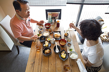 Woman and man sitting at a table, eating Japanese Food with chopsticks, Osaka, Japan