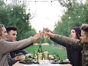 An apple orchard in Utah. Group of people toasting with a glass of cider, food and drink on a table, Sataquin, Utah, United States of America