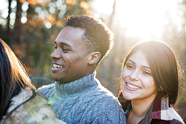 Smiling couple standing in a sunlit forest in autumn, Woodstock, New York State, USA