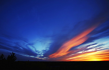 Shafts of sunlight from the setting sun illuminating the clouds in a darkening sky, 