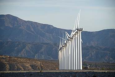 Wind power turbines in the landscape. A large number of turbine powers on a plain against a mountain backdrop, United States of America