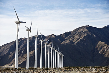 Wind power turbines in the landscape. A large number of turbine powers on a plain against a mountain backdrop, United States of America