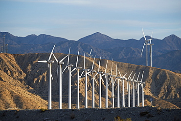 Wind power turbines in the landscape. A large number of turbine powers on a plain against a mountain backdrop, United States of America