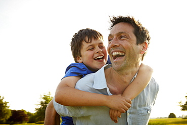 A father giving his son a piggyback, England, United Kingdom