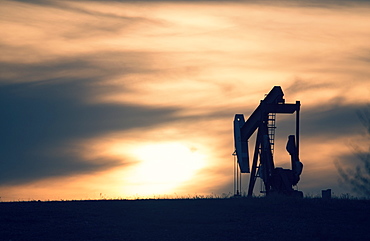 A pumpjack at an oil drilling site at sunset, Oilfield pumpjack, Canada