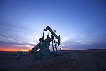 A pumpjack at an oil drilling site at sunset, Oilfield pumpjack, Canada