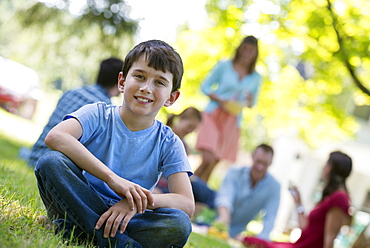 A group of adults and children sitting on the grass under the shade of a tree. A family party, Woodstock, New York, USA