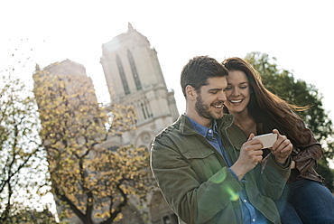 A couple in a historic city, looking at a smart phone, France