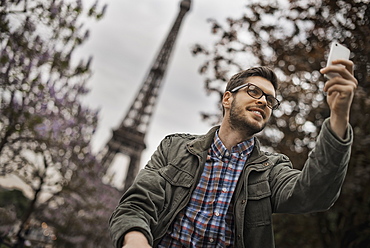 A man sitting on a park bench in the Champs de Mars under the Eiffel Tower, France