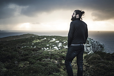 A man standing looking out over the landscape at sunset, Scotland, United Kingdom