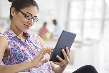 Professionals in the office. A light and airy place of work. A young woman seated using a digital tablet, New York City, USA