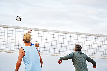 Mature men standing on a beach, playing beach volleyball, United States of America