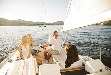 Man, woman and their two blond daughters on a sail boat.